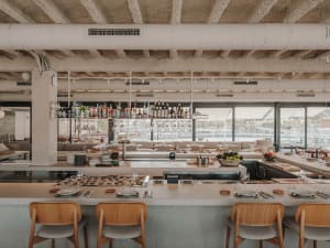 A restaurant interior with a bar and dining tables, featuring bottles and a welcoming atmosphere