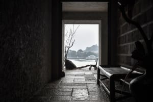 A small, dark room with a stone wall and a bench, creating a calm and quiet atmosphere