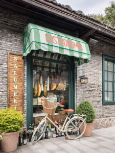 A charming brick storefront with a parked bicycle and surrounding bottles, evoking a sense of a quaint neighborhood shopping experience