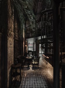 A cozy restaurant with a bar area and multiple dining tables, surrounded by chairs for guests to socialize and enjoy food and drinks