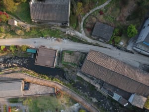 Two rustic houses with brick walls, one older than the other, situated on a hillside in a peaceful environment