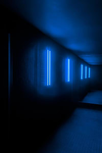 A dark hallway with bright blue lights lining its walls, creating a contrast between darkness and blue glow