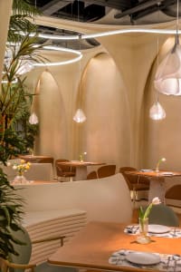 Clean and modern dining space with white walls, tables, and chairs, emphasizing simplicity in design