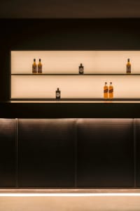 A bar area with a wooden counter featuring several bottles of liquor, creating a cozy and inviting atmosphere for socializing