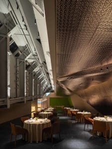 A modern restaurant interior with set tables, chairs, and decorative items, creating a welcoming atmosphere for guests