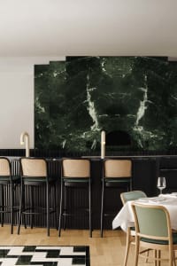 Sophisticated restaurant interior with marble walls, green accents, and comfortable seating for dining
