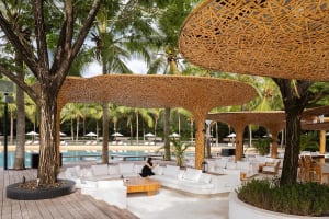A relaxing outdoor patio with white couches, umbrellas, and a comfortable seating area