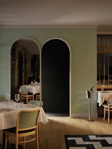 Elegant dining area with a large wooden table and chairs, surrounded by tasteful decorations and well-lit spaces