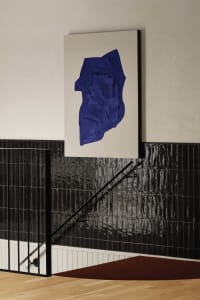 A modern staircase with black steps and a large blue painting above, creating a striking contrast in a contemporary space