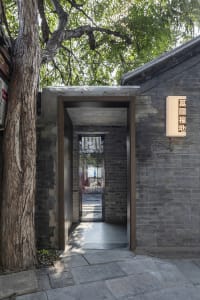 A small room with a stone wall, brick floor, and two windows, creating a calm and serene atmosphere