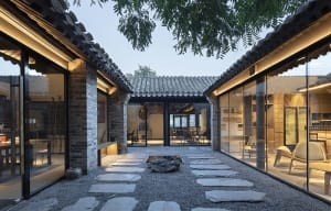 A serene Asian-style house with a courtyard area featuring a rock garden, stone walls, and tiled roofs