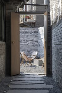A cozy living room with a dining table and two chairs, with a doorway leading to a patio area