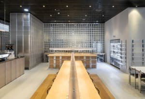 Industrial dining space with wooden tables and chairs, multiple dining tables and chairs arranged for efficient food preparation and serving