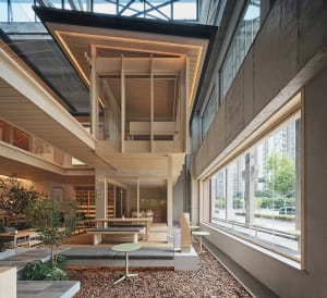Open modern living area with a wooden floor, natural light, and various furniture pieces and decorative items