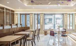 A warm and inviting restaurant interior with multiple dining tables and chairs, featuring a mix of natural and artificial lighting