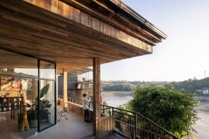 A serene riverfront scene with a woman taking a photo, surrounded by a wooden deck and scenic views