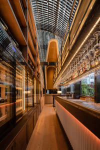 A modern bar area with a long counter featuring wine glasses and bottles, set in a sophisticated atmosphere