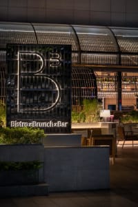 Modern restaurant interior with a bar and dining area, featuring chairs, tables, and bottles, creating a cozy atmosphere