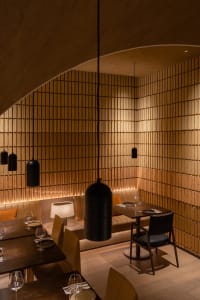 Warm and inviting dining area with a long wooden table, chairs, and wine glasses, perfect for socializing and enjoying meals