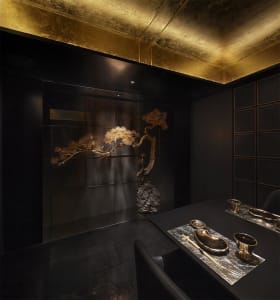Bathroom with two bowl sinks, gold-toned fixtures, and artwork on the walls