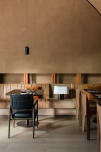 A warm and inviting dining space with wooden walls and floors, featuring multiple chairs and tables with wine glasses, creating a comfortable atmosphere for guests