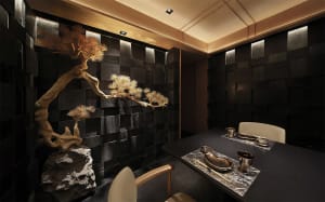 Elegant dining space with a wooden table, black tile floor, and stone wall, featuring Asian-inspired decor and a warm atmosphere