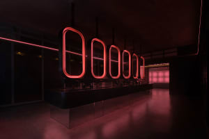 Modern kitchen with a black countertop, red lighting, and mounted clocks on the wall