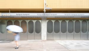A commercial building with two large glass doors, one on either side, with the word Konpan written in white letters, made of concrete