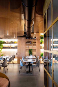 Warm and inviting restaurant interior with wooden walls and ceiling, wine bottles, and multiple dining tables and chairs
