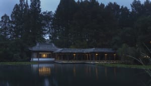Asian-style building near a body of water with a distinctive roof design, natural light entering through windows, and a serene atmosphere