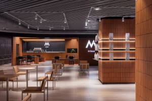 A cozy restaurant interior with multiple seating areas, dining tables, and potted plants, creating a welcoming atmosphere