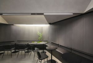 A cozy dining area with several tables and chairs, featuring plants and an inviting atmosphere
