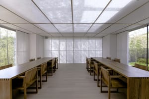 A clean and well-organized restaurant with wooden tables and chairs, white walls, and a bright atmosphere