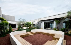 Architectural rendering of a building's exterior featuring a patio with potted plants and a bench, creating a welcoming and relaxing atmosphere