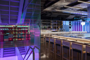 A cozy bar area with a long wooden dining table surrounded by chairs, bottles, and a warm atmosphere