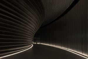 A calm and inviting interior hallway with a curved design, marble flooring, and two people standing near the center