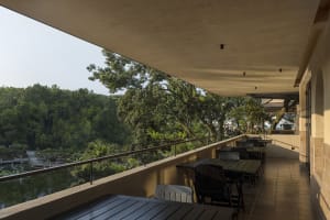 A restaurant patio with multiple dining tables and chairs overlooking a forest, creating a serene atmosphere