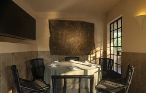 A well-lit dining area with a large table set for a meal, surrounded by chairs and vases, with a rock wall adding a unique touch to the space