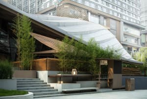 A modern building with a curved glass roof and potted plants in various sizes and positions around the exterior