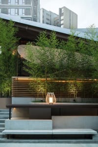 A modern building with a wooden table and surrounding potted plants, conveying a sense of tranquility and harmony between indoor and outdoor spaces