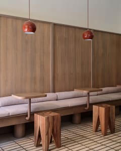 A modern dining space with wooden walls and tables, featuring three dining tables with chairs, creating a warm and inviting atmosphere for socializing and dining