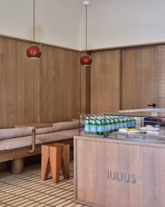 Cozy restaurant interior with wooden walls and floors, featuring a dining table, couches, and bottles on a countertop