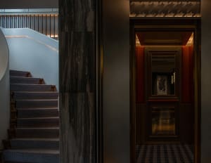 A luxurious hallway with a marble floor, a staircase, and two doors, set in a sophisticated and elegant environment