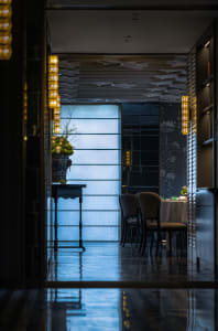 A well-lit dining area with a large table surrounded by multiple chairs, set with various items, conveying a sense of luxury and comfort