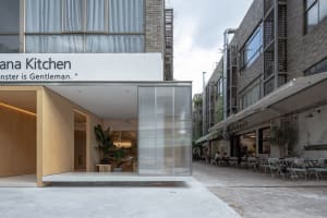 A modern building with a glass front entrance, surrounded by potted plants and seating areas, conveying a sense of sophistication and elegance