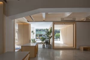 Open office space with wood flooring, white walls, potted plants, chairs, and a dining table