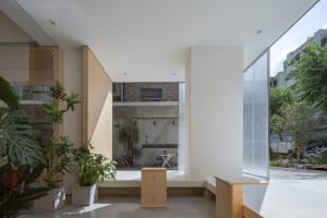 A clean and organized living area with a white wall, a window, wooden storage units, and potted plants