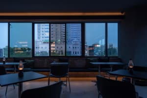 A modern restaurant with glass surfaces, contemporary furnishings, and a comfortable seating area with chairs arranged around dining tables near large windows