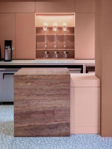 A modern kitchen with a marble countertop island, wine glasses, and a coffee maker, featuring warm and inviting lighting