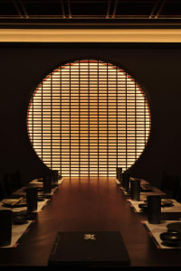 A cozy dining area with a round table surrounded by chairs, set with bowls and cups, in a restaurant-like setting